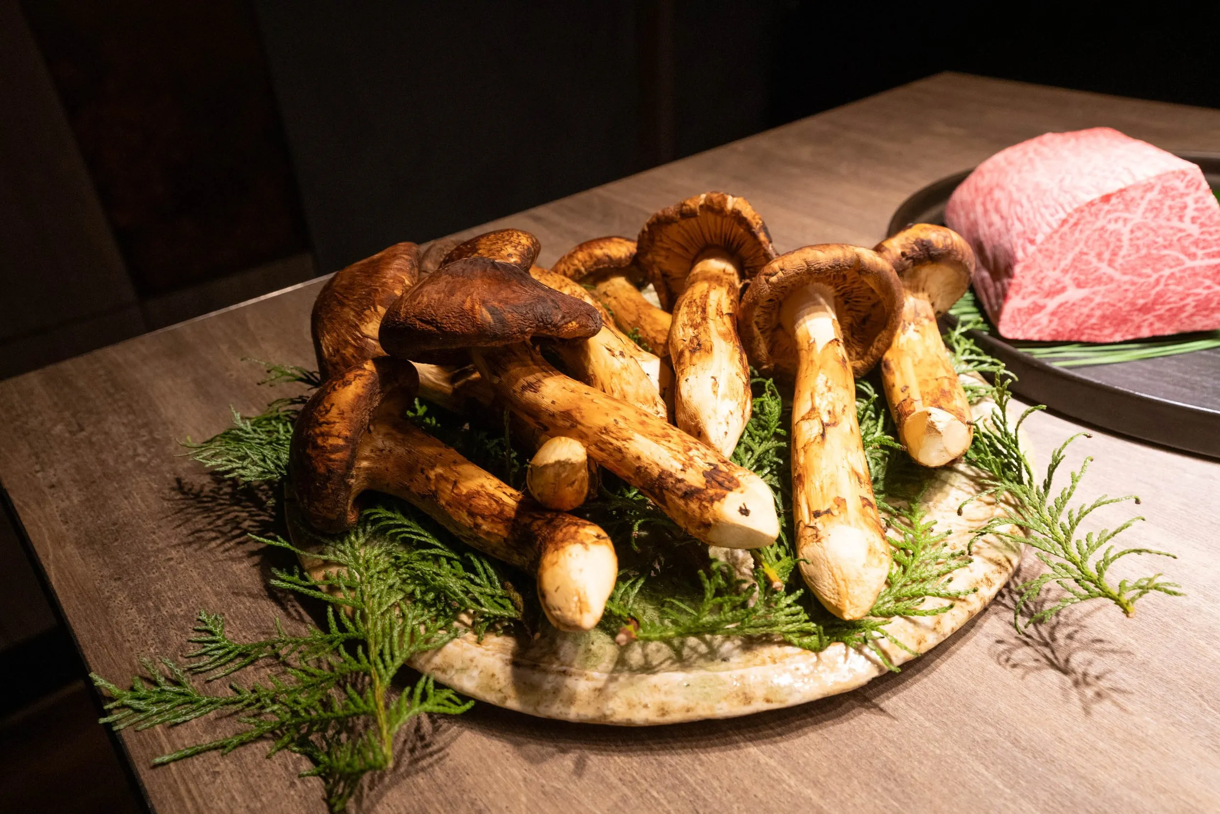 Matsutake mushrooms and a block of marbled wagyu, presented at the start of the meal