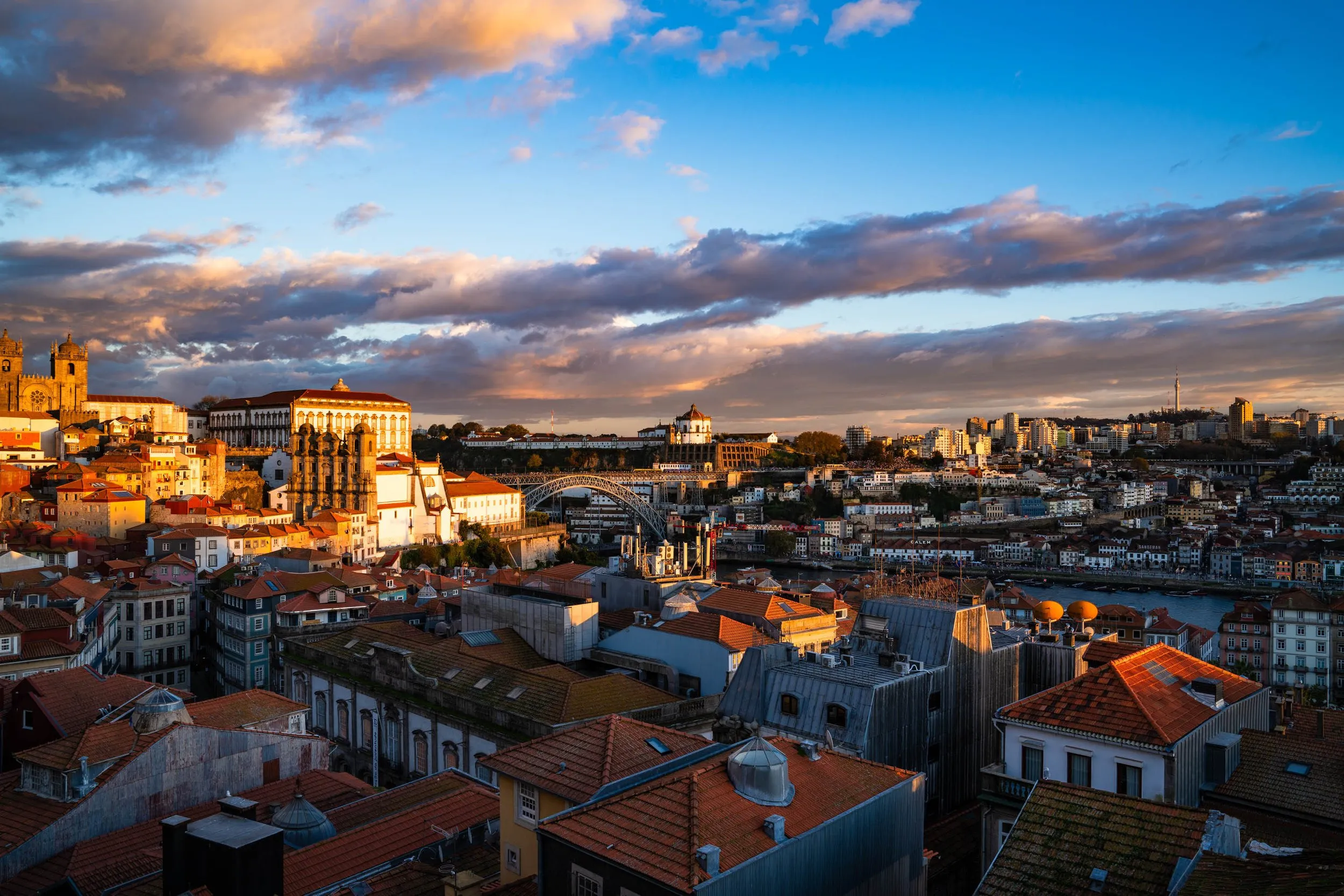 Porto's red rooftops and church towers at sunset under a blue sky with long clouds