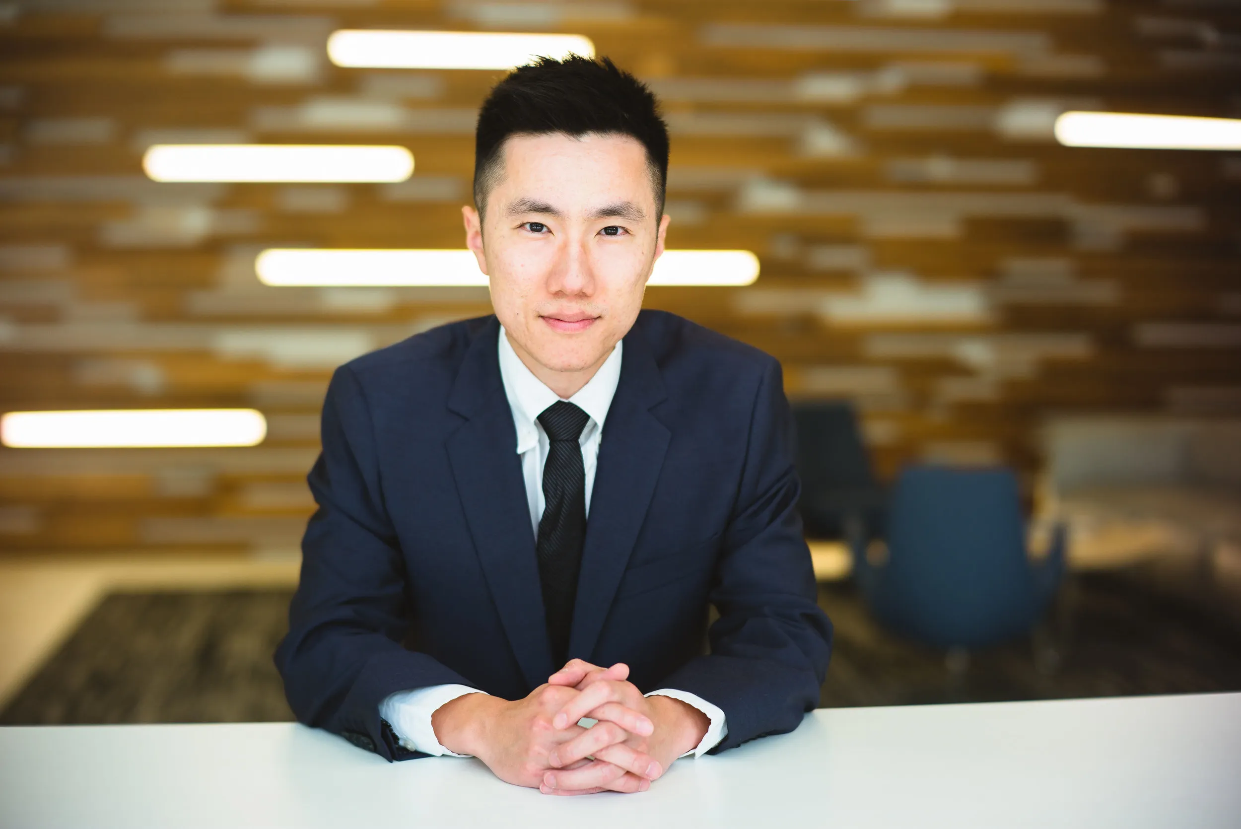 Jerry Zhou in a navy suit, hands folded on a white table.